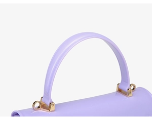 Détail macro du sac en PVC lavande avec finition brillante et ferrures dorées