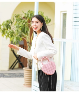 Outdoor lifestyle shot of a pink heart-shaped quilted PVC jelly bag with gold chain strap