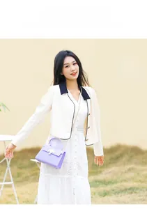 Détail du sac violet avec fermoir floral doré et bandoulière en chaîne porté par le mannequin