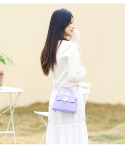 Détail du mini sac à main en PVC violet avec fermoir fleur de lys doré et chaîne en métal