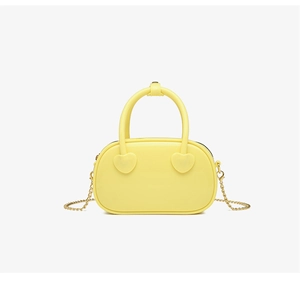 Detailed view of bright yellow jelly bag with heart accents and gold chain strap