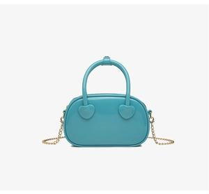 Detail of trendy blue PVC jelly bag featuring a heart ornament and gold chain strap