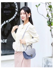 Détail d'un sac selle bleu clair semi-transparent avec boucle en argent et texture denim fine