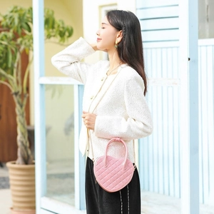Chic pink heart-shaped quilted PVC bag with gold chain strap carried by a model