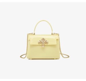 Détail du sac en PVC jaune clair avec fermoir fleuri doré et bandoulière chaîne