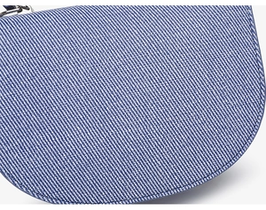 Vue macro du tissu en sergé bleu et blanc et des garnitures argentées du sac selle