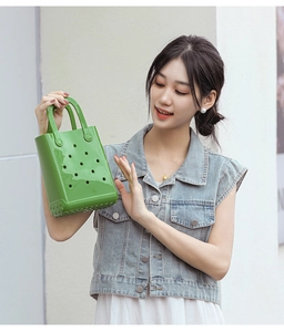 Detail shot of bright green EVA beach bag with holes held by a model in denim