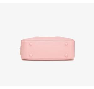 Vista detallada de la base del bolso de PVC rosa con tacos protectores de metal dorado