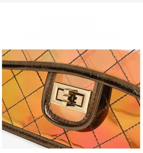 Close-up of orange holographic PVC crossbody bag with diamond quilting and gold lock