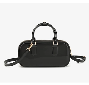 Detalle de bolso Boston de PVC negro brillante con herrajes dorados y correa ajustable