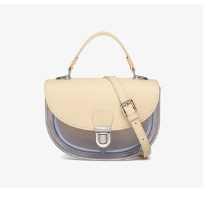 Gros plan d'un sac selle semi-transparent avec rabat en tissu beige et fermoir argenté