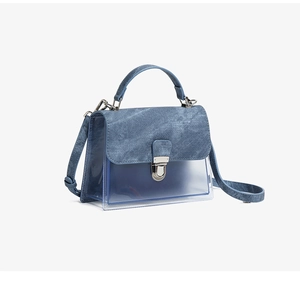 Detalle de la tela vaquera azul y material de PVC transparente en el bolso de moda
