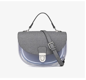 Détail du sac selle translucide avec rabat à rayures grises et pochette bleue