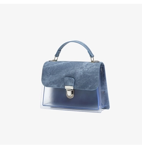 Detalle de bolso de mezclilla azul y PVC transparente con cierre plateado y textura de tela