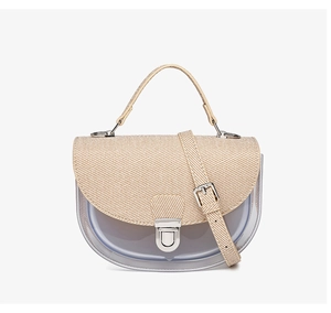 Détail du sac selle translucide avec rabat tissé beige et boucle métallique argentée