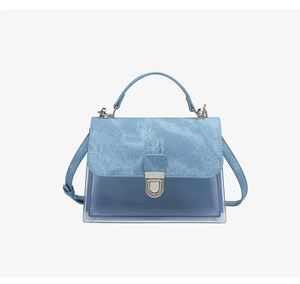 Detalle del bolso de PVC azul claro con solapa de textura denim y cierre de metal plateado