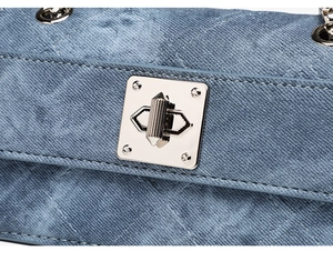 Detail of silver twist lock and V-stitch quilting on blue denim crossbody bag