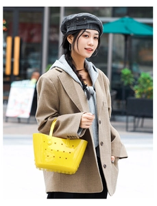 Détail du sac cabas en EVA jaune perforé porté par un mannequin dans un style de rue décontracté