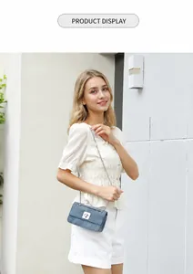 Detail of light blue denim crossbody bag featuring silver chain strap and metal twist lock