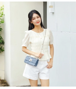 Close-up of white bubble sleeve shirt with pleated texture and blue chain crossbody bag