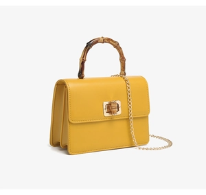 Detalle de asa de bambú y cierre dorado en bolso de cuero sintético amarillo