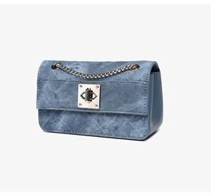 Detailed side view of denim blue crossbody bag with silver chain and metal lock
