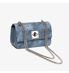 Detail view of denim crossbody bag with silver metal chain strap and square turn-lock closure