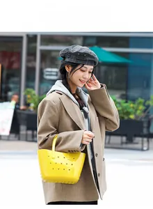 Gros plan d'un sac panier jaune en PVC avec motifs d'étoiles évidées porté par un modèle
