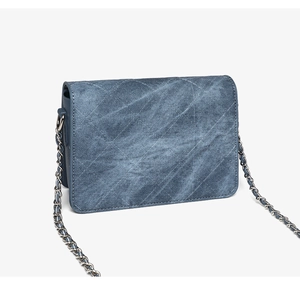 Dettaglio della borsa trapuntata in denim blu con tracolla a catena in metallo argento