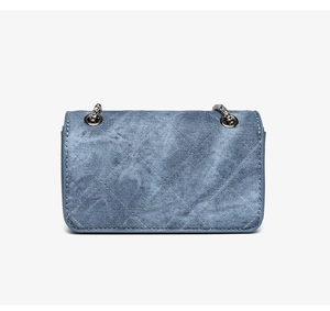 Detailed view of blue denim quilted texture and silver chain strap on a vintage bag