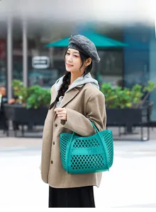 Detail view of teal镂空 jelly tote bag made of waterproof plastic material outdoors