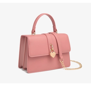 Detalle lateral del bolso bandolera de cuero PU rosa con cierre de corazón dorado y fuelle triple