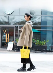 Street style shot of a bright yellow PVC hollow out jelly handbag with star decorations