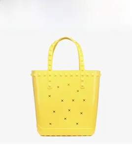 Detail view of bright yellow PVC beach tote with star cutouts and pyramid stud accents