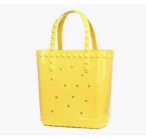 Macro view of bright yellow PVC beach bag featuring star cutouts and rivet accents