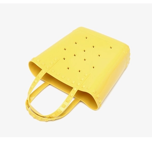Detailed view of bright yellow hollowed PVC beach tote bag with rivet decorations