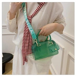 Dettaglio borsa jelly verde trasparente con tracolla larga logata e mini ciondolo