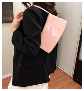 Bolso baguette rosa de charol brillante combinado con blazer negro y un vestido