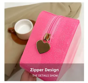 Detail of glittery pink cosmetic bag featuring a polished gold heart-shaped metal zipper