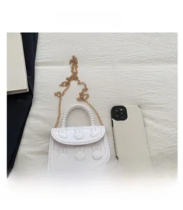 Detailed comparison of white bunny purse size next to a smartphone with pearl handle