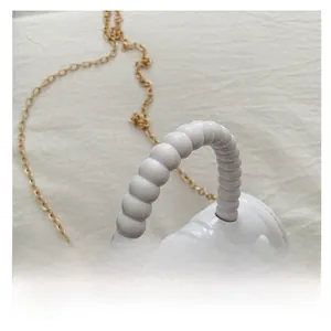 Detail of beaded bubble handle and smooth white leather finish on kids square bag
