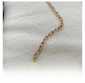 Detailed macro view of a polished golden metal chain strap on a white fabric background