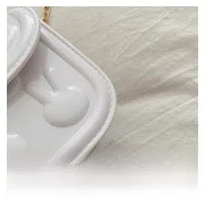 Macro shot of stitching details and embossed bunny on white glossy leather kids bag