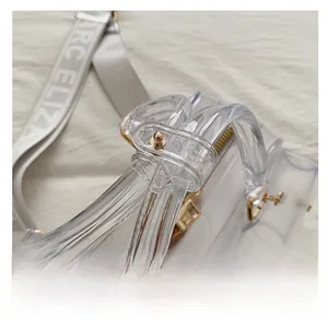 Detail view of transparent PVC jelly bag with golden zippers and branded strap