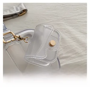 Detail of transparent PVC mini pillow bag with gold lobster clasp and branded strap