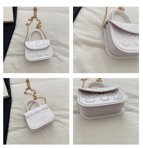 Detail view of white rabbit crossbody bag with pearl handle and golden chain strap
