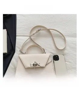 Vue détaillée du sac bandoulière crème avec fermoir argenté et smartphone pour la taille