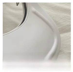 Detailed close-up of glossy white faux leather texture and smooth metal zipper on bag