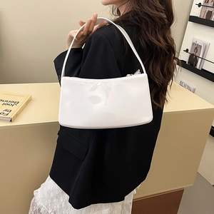 Bolso baguette minimalista de charol blanco llevado al hombro con estilo moderno