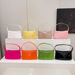Bolsos de hombro en cuero sintético en ocho colores vibrantes sobre un soporte blanco